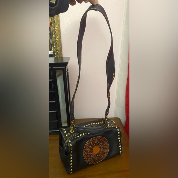 Black leather cross body purse with orange colored medallion on front. - Picture 2 of 14